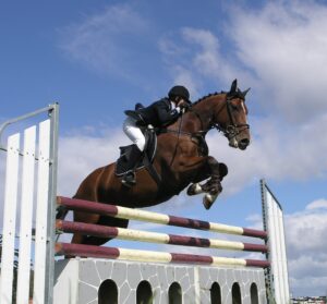 horse and rider clearing a very tall jump 