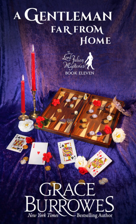 The cover image for A Gentleman Far From Home, Book Eleven in the Lord Julian Mysteries, by NYT Bestselling author Grace Burrowes. A still life composition of a backgammon board, red candles, and playing cards lay atop a rich purple velvet backdrop. Flowers and coins are scattered around the scene.