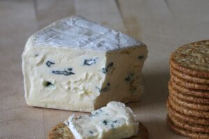 A hunk of cambozola cheese and a stack of round crackers